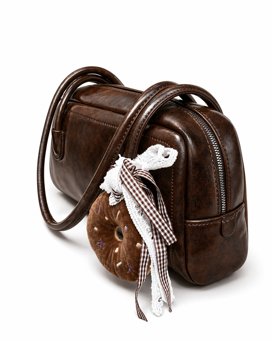 BOLSO BAGUETTE EN CUERO SINTÉTICO, CHARM DE PELUCHE DONA Y BOLSILLO INTERNO.