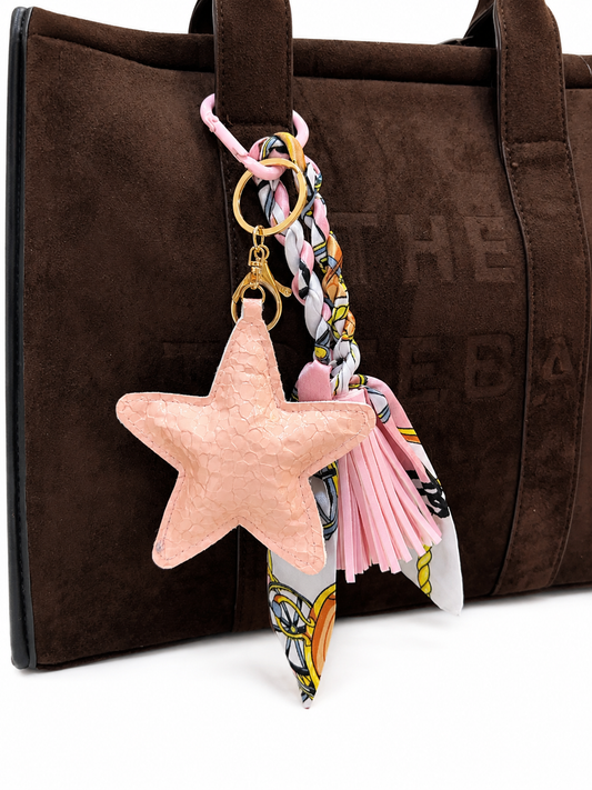 CHARM DE ESTRELLA BRILLANTE CON PAÑOLETA TRENZADA Y BORLA DE TIRAS EN CUERO SINTÉTICO.